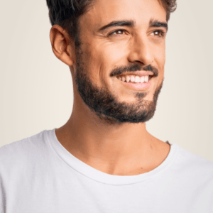 Man smiling and looking to the side, wearing a white t-shirt against a light background representing the cut service. Link goes to services page.